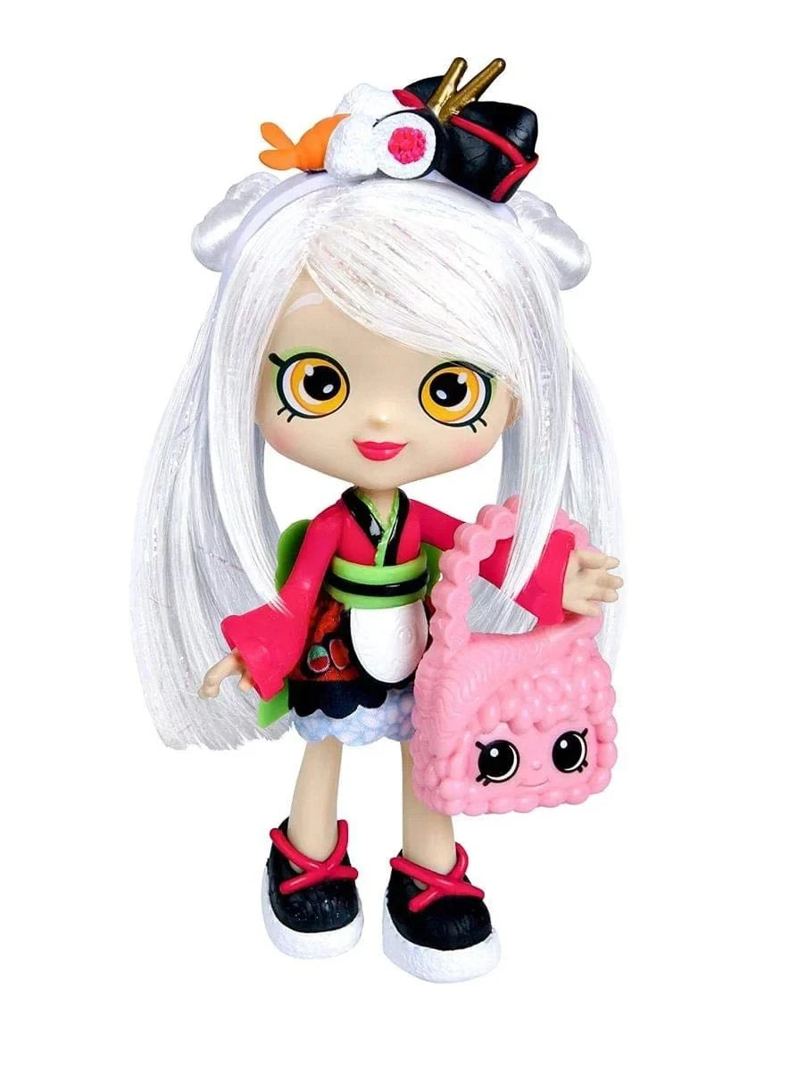 Toy doll with white hair and colorful outfit holding a pink bag on a white background